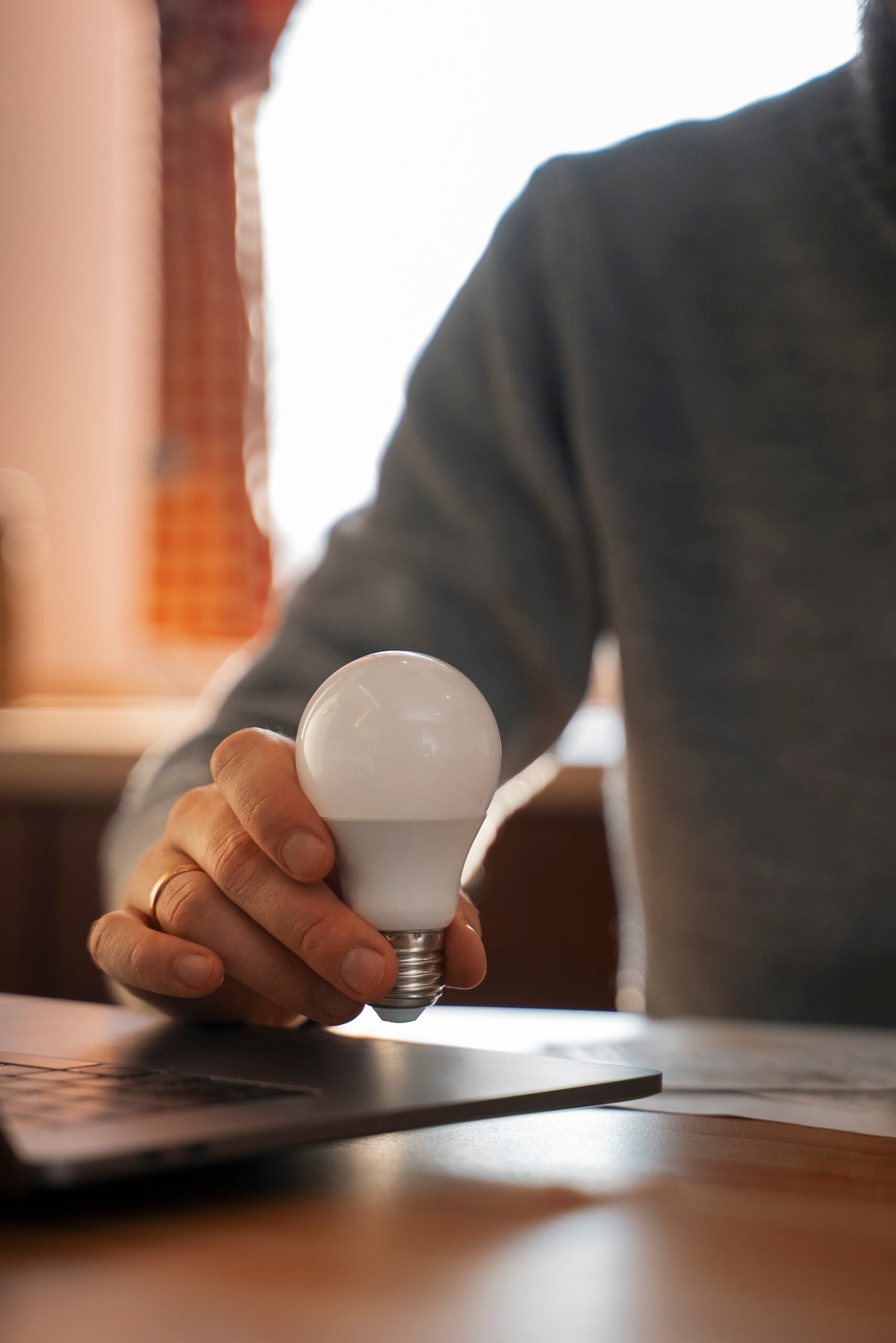 Persona revisando una factura de luz en casa junto a gráficos de consumo energético y comparativa de tarifas.